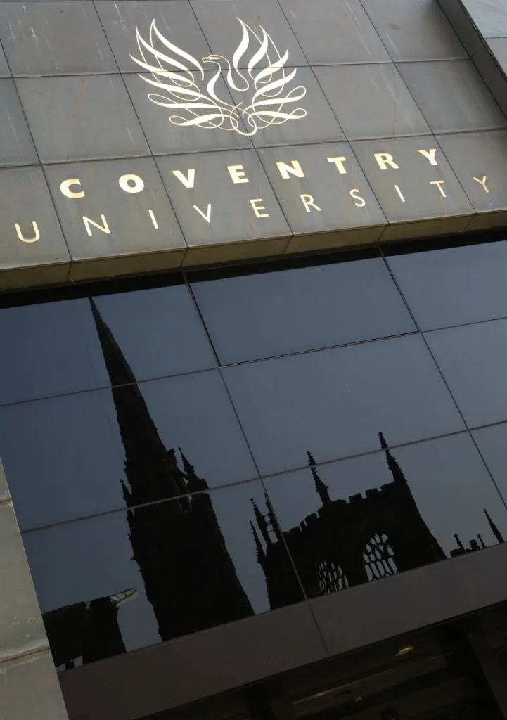 Vstup do budovy Coventry University s logom fénixa a odrazom katedrály vo fasáde
