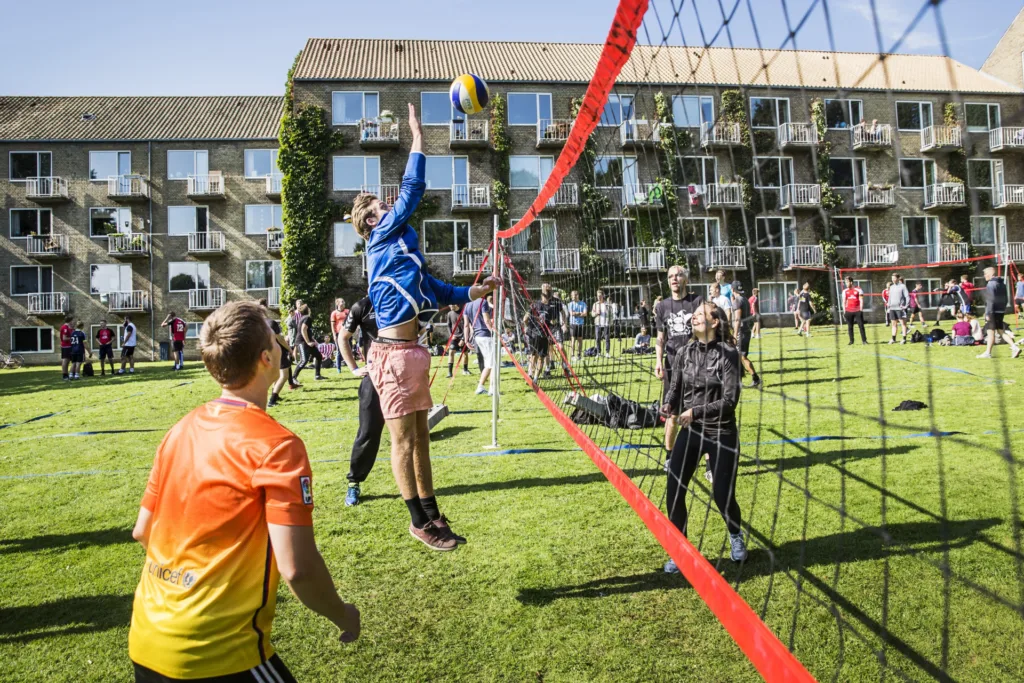Študenti hrajú volejbal na trávniku pred internátom Aarhus University