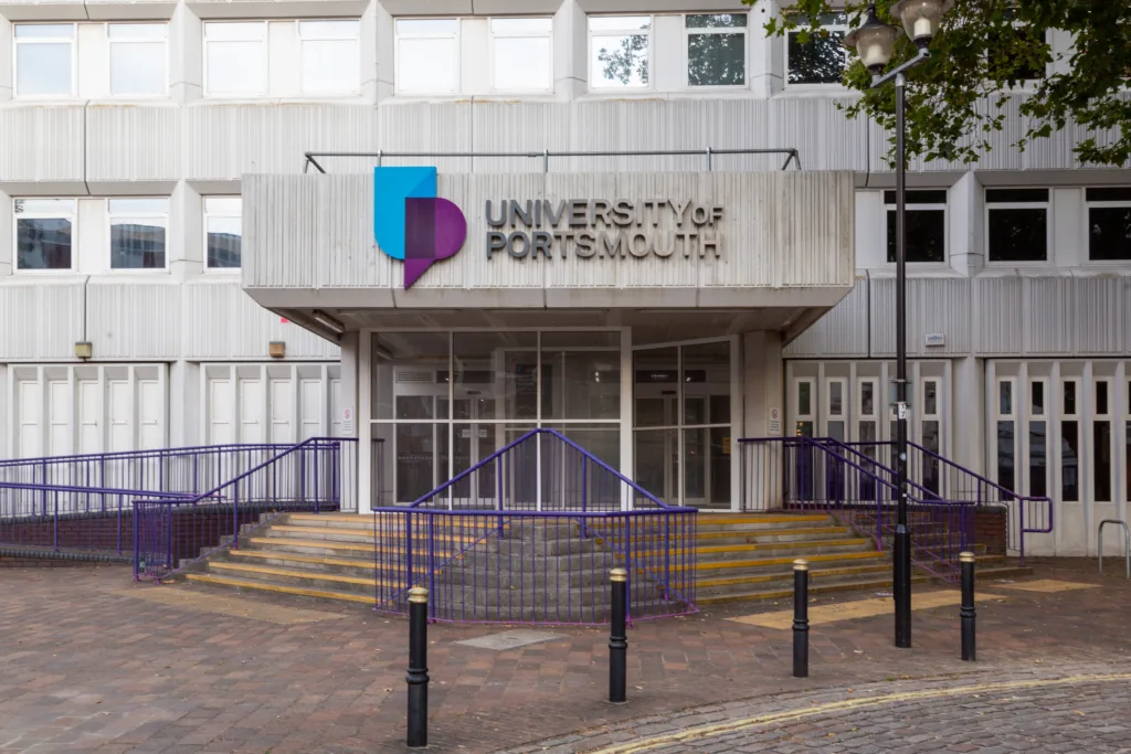 Vchod do budovy University of Portsmouth s logom a fialovým zábradlím