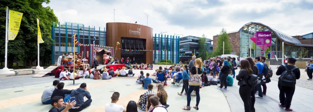 Študenti sledujú vystúpenie na námestí pred kampusom Coventry University